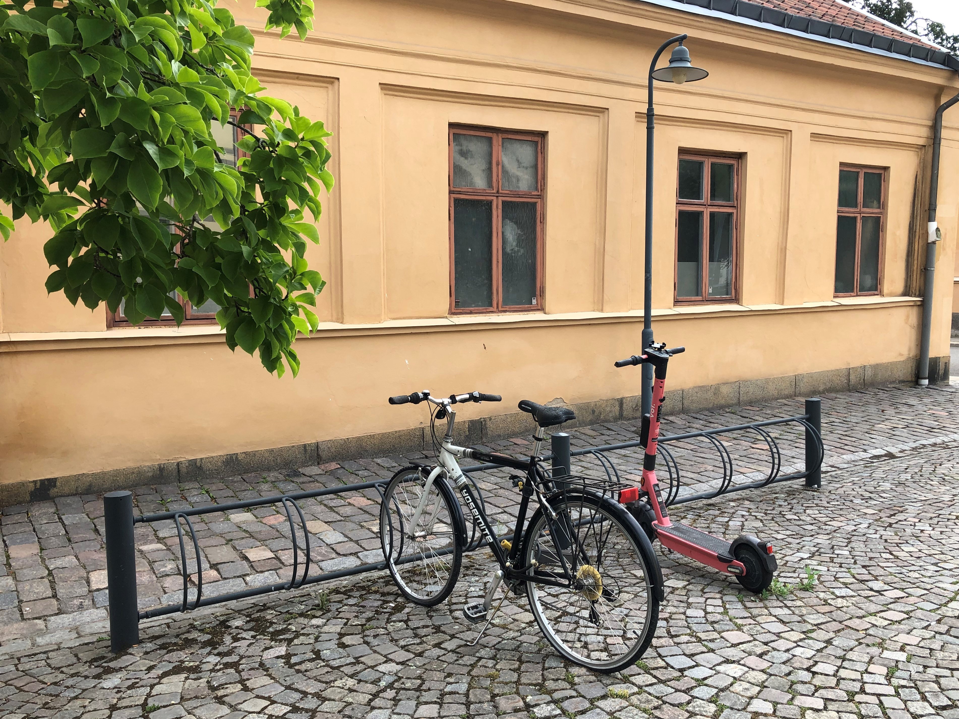 Cykelställ med vanlig cykel och elsparkcykel parkerade.