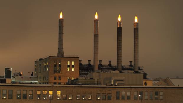 Fyra stora skorstenar på en industrihus är ljussatta som adventsljus. 