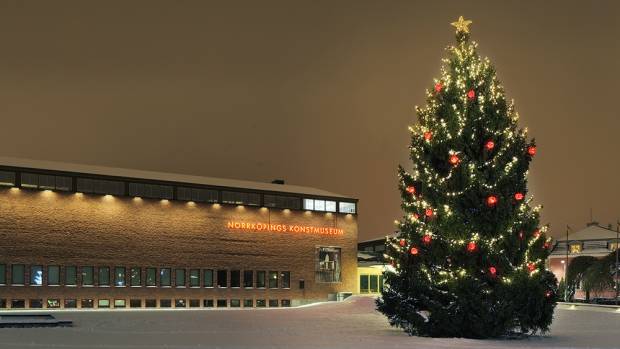 En stor julgran klädd med lysande julkulor, ljusslingor och en lysande stjärna högst upp.