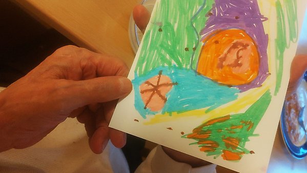En äldre dam håller i ett Alla hjärtans dag-kort som ett barn har målat.
