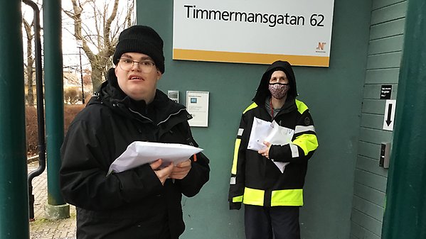 Två personer från Packman står vid ingången till Träffpunkten Timmermansgatan 62.
