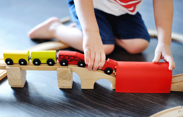 Ett barn leker med en tågbana i trä